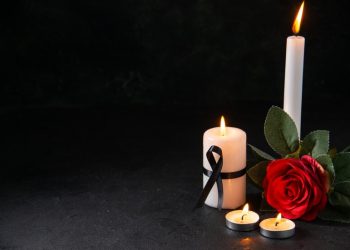 front-view-burning-candle-with-red-flower-dark-surface_