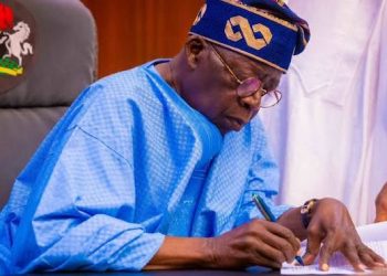 President Bola Ahmed Tinubu signing a document.
