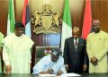 President Tinubu signs NIMC Bill into law watched by lawmakers and NIMC officials.