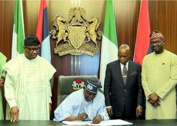 President Tinubu signs NIMC Bill into law watched by lawmakers and NIMC officials.