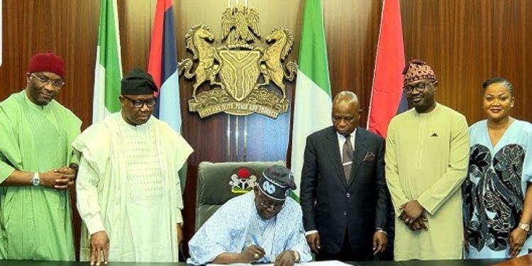 President Tinubu signs NIMC Bill into law watched by lawmakers and NIMC officials.