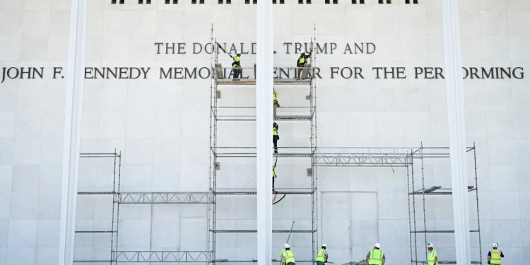 Workers stand on scaffolding near the signage for the Donald J. Trump and John F. Kennedy Memorial Center for the Performing Arts in Washington