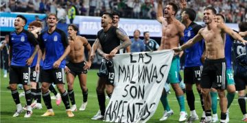 Argentine players display a banner making claims to Falklands Islands against FIFA rules.