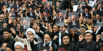 Shia Muslims holding portraits of Iran's Supreme Leader Mojtaba Khamenei and late leader Ali Khamenei