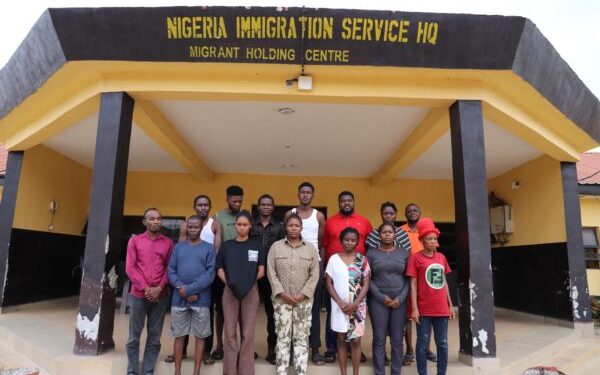 Twelve suspects arrested by the Nigeria Immigration Service stand outside the agency's Migrant Holding Centre