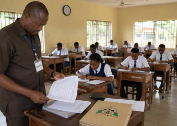 An invigilator supervises students writing an examination in a classroom