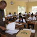 An invigilator supervises students writing an examination in a classroom