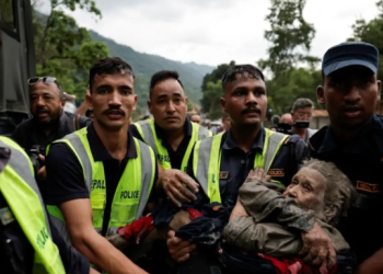 Rescue team members carry an elderly survivor to safety following devastating flash floods and landslides in Nepal.