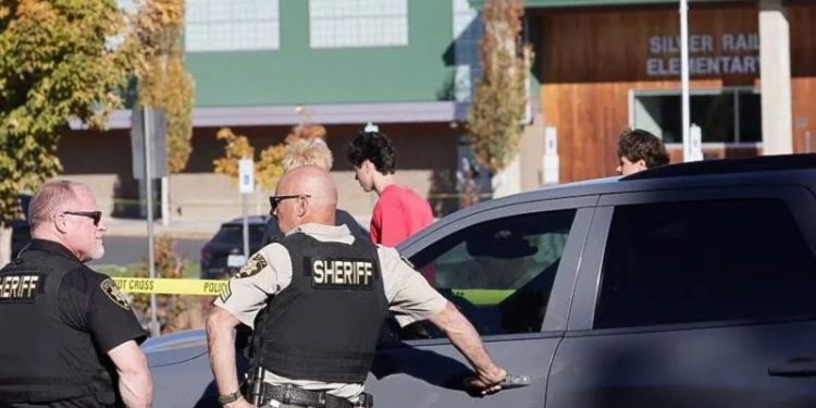 Local police officers stand beside their vehicles outside Silver Rail Elementary School following a deadly shooting in Oregon. (photo credit: BBC News)