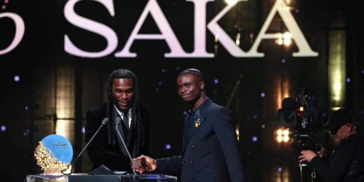 Nigerian singer Burna Boy presents the Sócrates Award to Arsenal and England forward Bukayo Saka at the 2026 Ballon d’Or ceremony in London.
