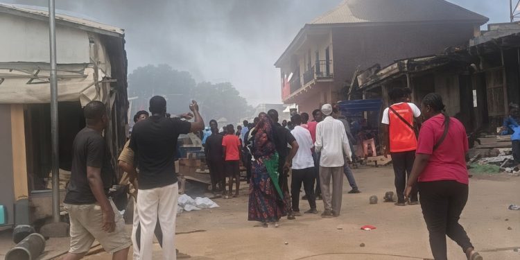 Traders stand near the scene of a fire outbreak at Kugbo Furniture Market in Abuja.
