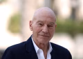 Late British actor Sir Patrick Stewart smiling in a dark suit, best known for his roles as Captain Jean-Luc Picard in Star Trek and Professor X in X-Men.