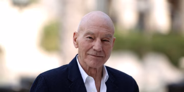 Late British actor Sir Patrick Stewart smiling in a dark suit, best known for his roles as Captain Jean-Luc Picard in Star Trek and Professor X in X-Men.